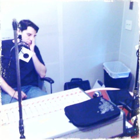 Marc at the mic in a bare-walled studio